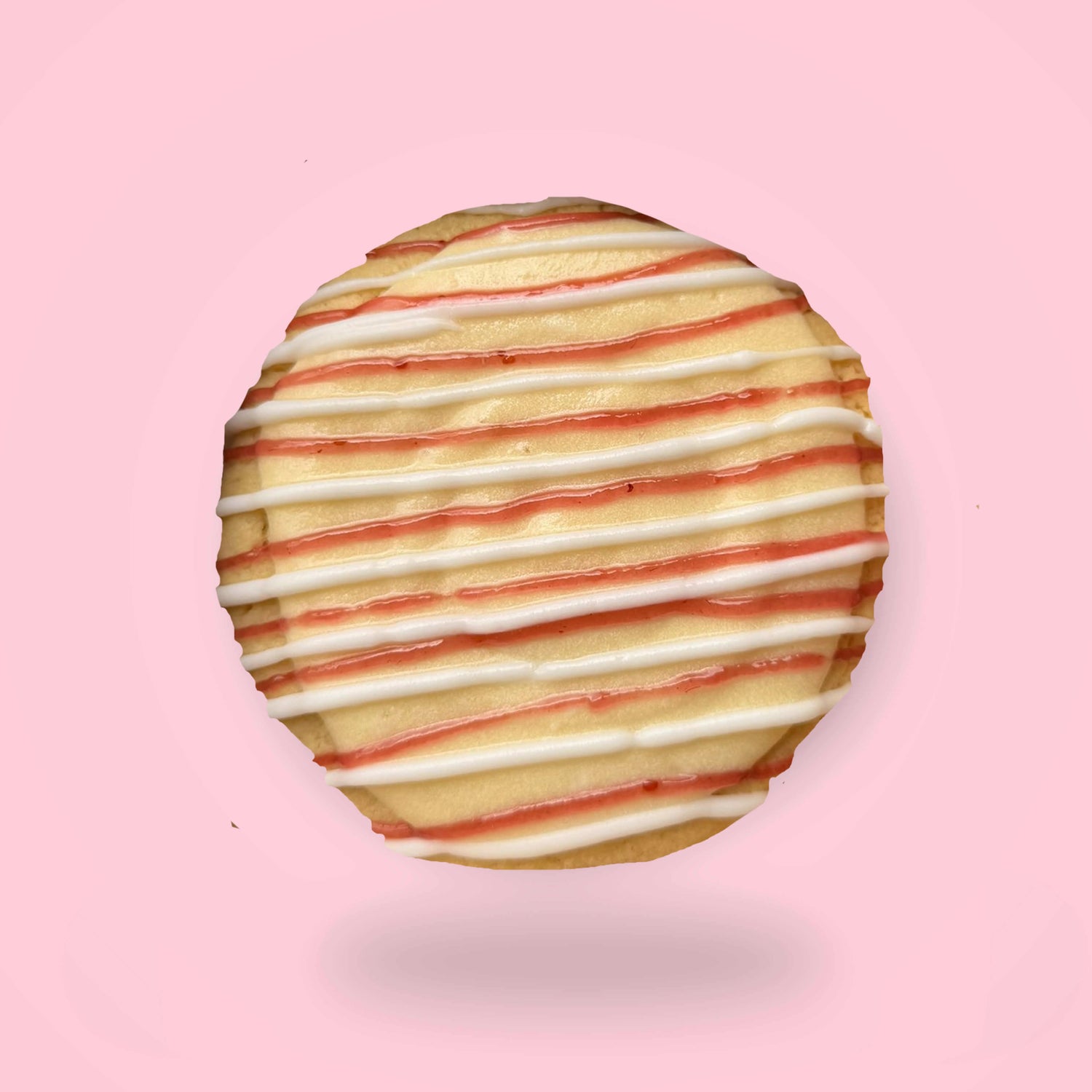Cookie with custard buttercream with white and red drizzle on a pink background