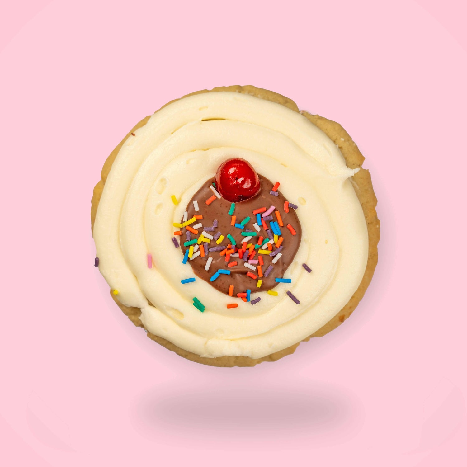 Cookie with white frosting, chocolate center, and colorful sprinkles on a pink background