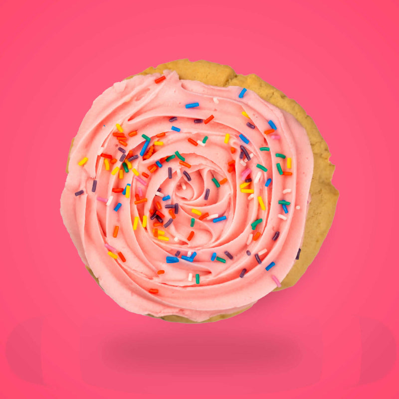 A pink birthday sugar cookie with colourful sugar strands